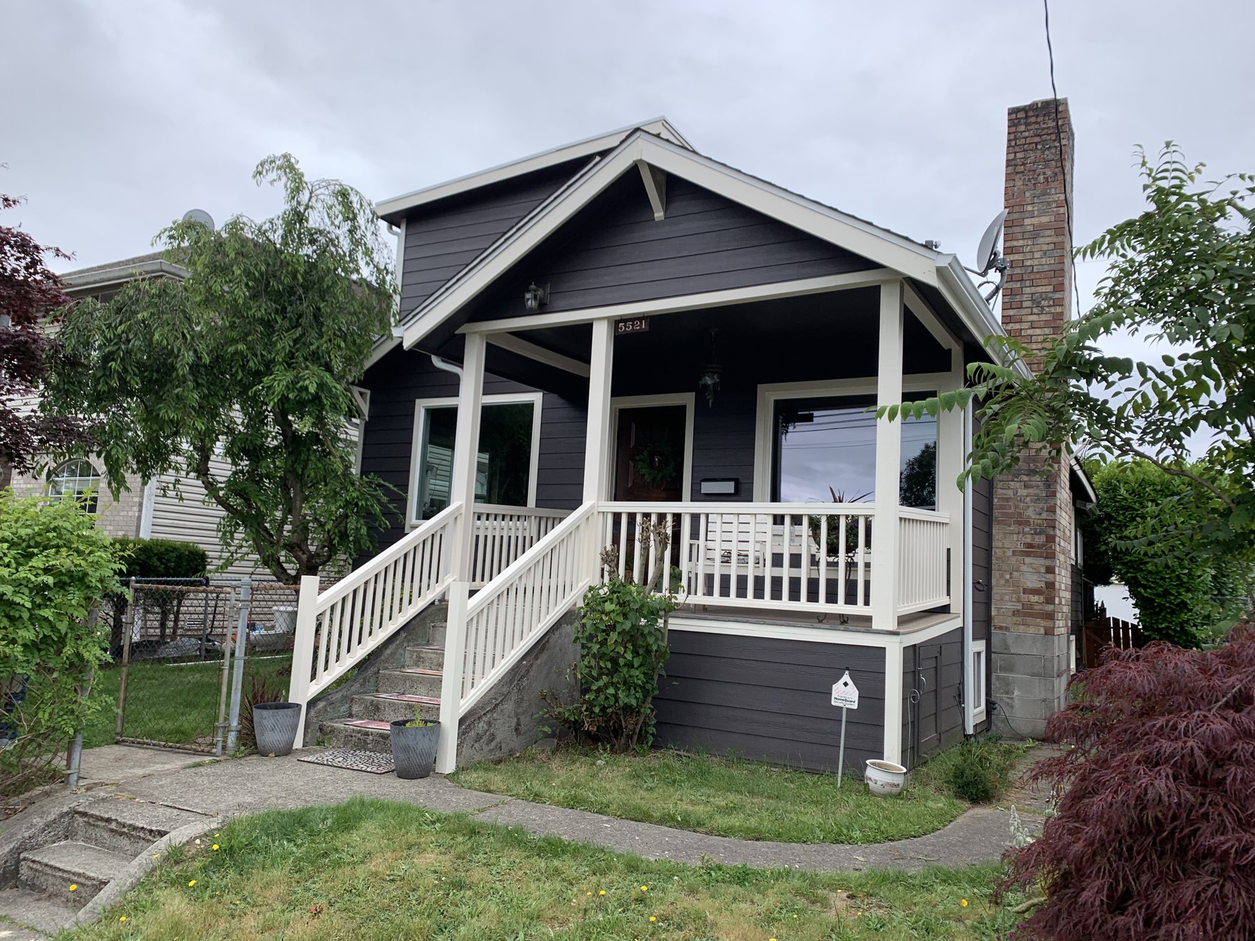 Charcoal Craftsman home with white porch railings and trim