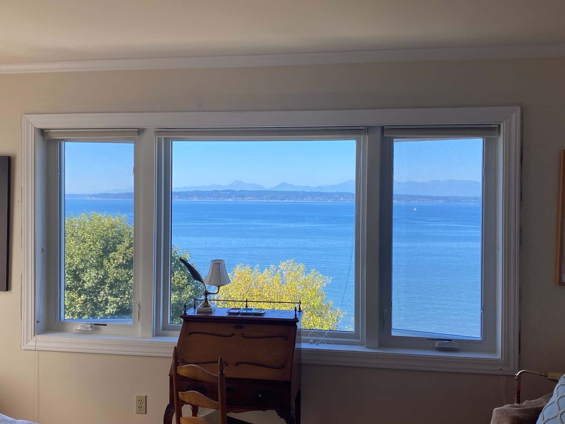 Painted interior walls and white window trim framing a water view